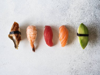 Smoked eel, salmon, tuna, shrimp and avocado sushi on grey background clipart