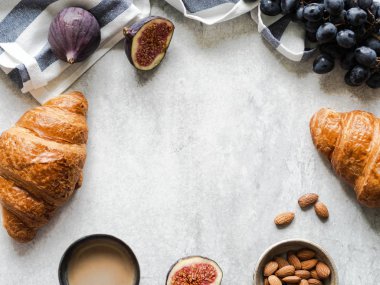 Kahvaltı çerçevesi kruvasan, incir, badem ve espresso ile gri arka planda, üst manzara, kopyalama alanı