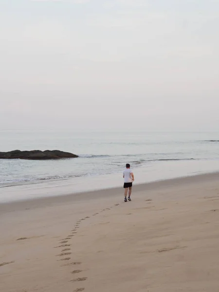 Uncertain man runs along a sandy beach in Thailand. Morning run along the seashore