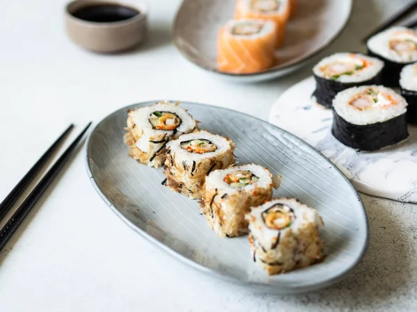 Seramik tabakta servis edilen karides, somon ve ton balıklı suşi rulolarının çeşitliliği..