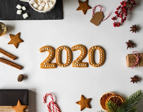 Gingerbread of the form of a numbers. 2020 new year ginger cookies and mug cacao with marshmallows and New Year\'s attributes on white background. Top view.