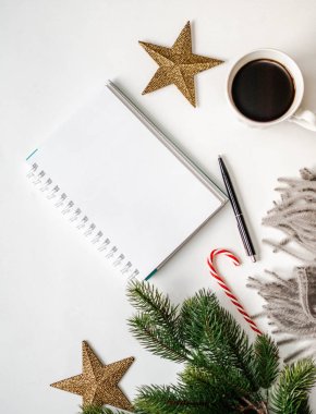 Sıcak gri ekose, kalemli açık defter, beyaz bardakta kahve ve beyaz arka planda Noel özellikleri. Üst Manzara. Boşluğu kopyala