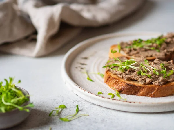 Deux rillettes de poulet grillées (pâté) sur pain blanc avec des germes sur plaque blanche sur fond clair. Espace de copie — Photo