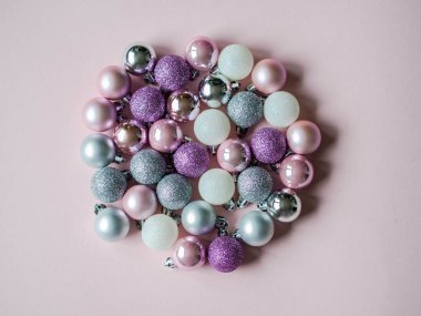 Pembe arka planda çember şeklinde çeşitli noel topları.