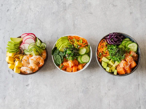 Flat lay Hawaiian salmon and shrimp poke bowls with seaweed, avocado, mango, raw vegetables, sesame seeds. Top view, copy space — Stock Photo, Image