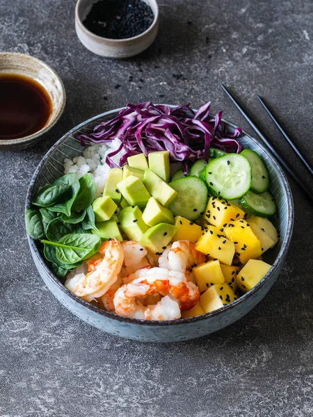 Hawaii karidesleri pirinç, avokado, salatalık, kırmızı lahana, mango, lahanalar, ıspanak ve gri arka planda susam tohumları. en üstteki görünüm