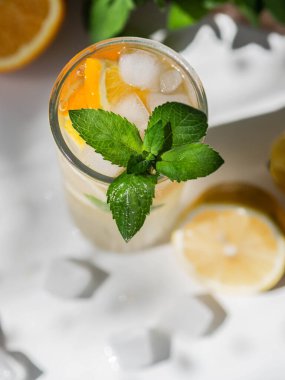 Taze yaz mevsimi portakal ve limon dilimli limonata, nane ve buzlu beyaz masa..