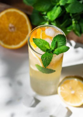 Taze yaz mevsimi portakal ve limon dilimli limonata, nane ve buzlu beyaz masa..