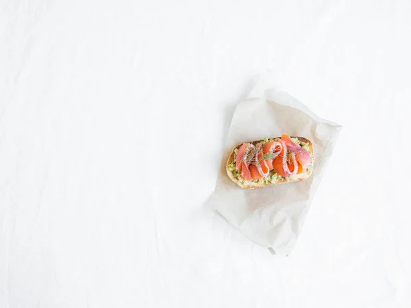Avocado and smoked salmon toast on the white papper on white background. Healthy food minimalist concept. Top view. Copy space