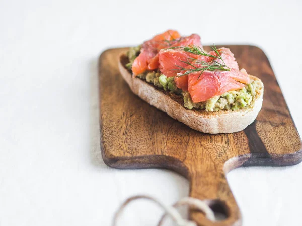 Avocado and smoked salmon toast on wood cutting board. Healthy food concept. Top view. Copy space