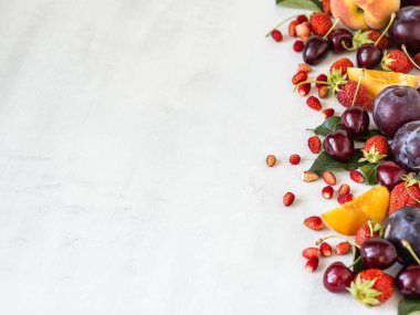 Beyaz arka planda çeşitli meyve ve meyveler. Çilek sınırı, yabani çilek, kiraz, şeftali, erik. Boşluğu kopyala