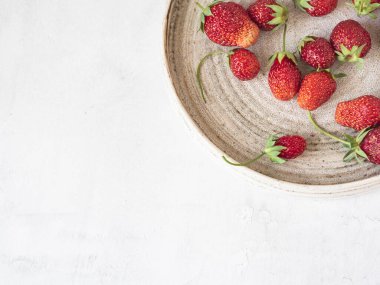 Beyaz arka planda eski bir tabakta taze koparılmış kırmızı çilekler. Üst Manzara. Boşluğu kopyala