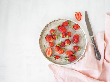 Beyaz arka planda eski bir tabakta taze koparılmış kırmızı çilekler. Üst Manzara. Boşluğu kopyala