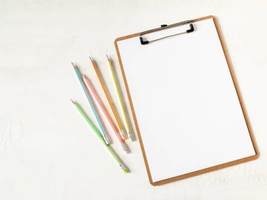 Beyaz sayfalı pano metin için kağıt kopyalama alanı ve beyaz arkaplanda çok renkli grafit kalemler. Düzlük, üst görünüm kız iş dünyası yaşam tarzı blogu konsepti