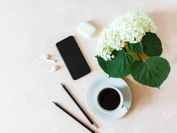 ピンクを基調としたブラックスマートフォン カップ入りブラックコーヒー ホワイトアジサイ ホワイトイヤホン 黒鉛鉛筆などのホームオフィスデスクワーク フラットレイ ライフスタイルブログのためのトップビューの女の子の仕事のビジネスコンセプト — ストック写真