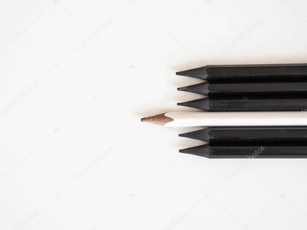 White pencil standing out same crowd black bold pencils on a white background, with space text. Leadership, unique, concept.