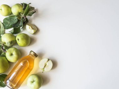 Cam şişede ev yapımı elma sirkesi. Fermente edilmiş elma suyu, taze elma ve beyaz arka planda yapraklar. Düz yatıyordu. Üst Manzara. Boşluğu kopyala