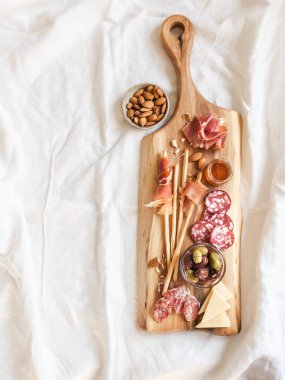 Atıştırmalık masası. Sosis, zeytin, peynir, ekmek çubukları, beyaz masa örtüsü üzerinde tahta kesme tahtası çeşitleri. Düz yatıyordu. Üst Manzara. Boşluğu kopyala