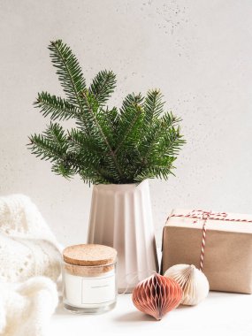 Modern seramik vazoda Noel ağacı dalları, hediye paketi ve rahat ev dekorasyonu. Ön manzara. Boşluğu kopyala