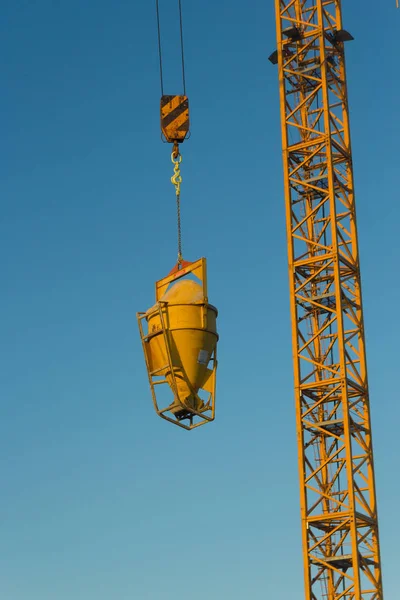 high crane concrete machine for spreading cement hoisted at building site on blue sky background