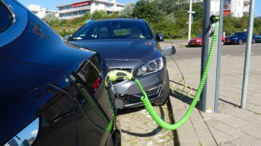 Kijkduin, Hollanda - 29 Haziran 2019: Tesla elektrikli otomobil ve hibrid volvo şarj pilleri Hollanda'da plug in charge station