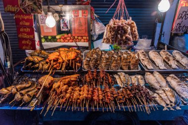 PATTAYA, THAILAND - 07 Temmuz 2018 'de Pattaya' da akşamları ızgara balık ve et satan geleneksel bir Tayland sokak yemeği standı.