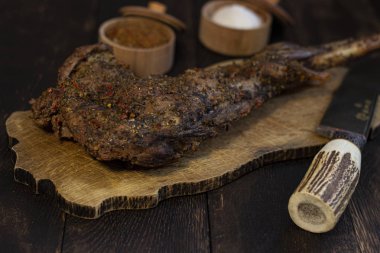 Baharat ve bıçak ile meşe masada Pişmiş keçi bacak