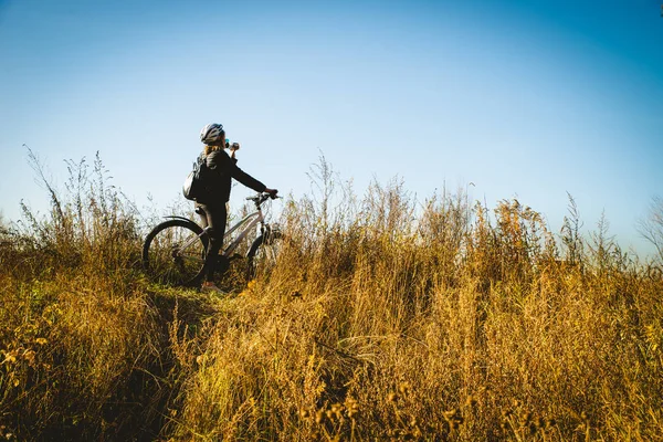 Genç kadın güneşli alanın karşısındaki bir bisiklet sürme tam çiçek.