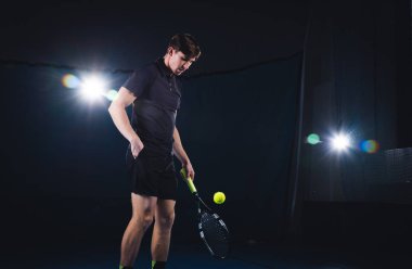 Bir adam tenis oynuyor. Kırmızı tişört bir erkekte bir tenis topu atıyor.