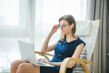 Gülümseyen mutlu kulaklıklı iş kadını masaya oturur, dizüstü bilgisayara bakar, notlar alır, kişisel gelişim webinarına katılır, internette eğlenir, video aracılığıyla iletişim kurar.