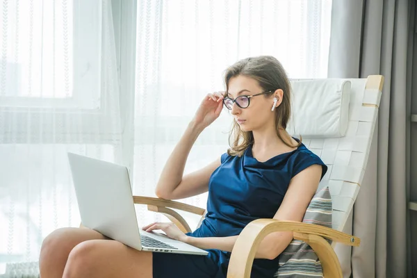 Gülümseyen mutlu kulaklıklı iş kadını masaya oturur, dizüstü bilgisayara bakar, notlar alır, kişisel gelişim webinarına katılır, internette eğlenir, video aracılığıyla iletişim kurar.