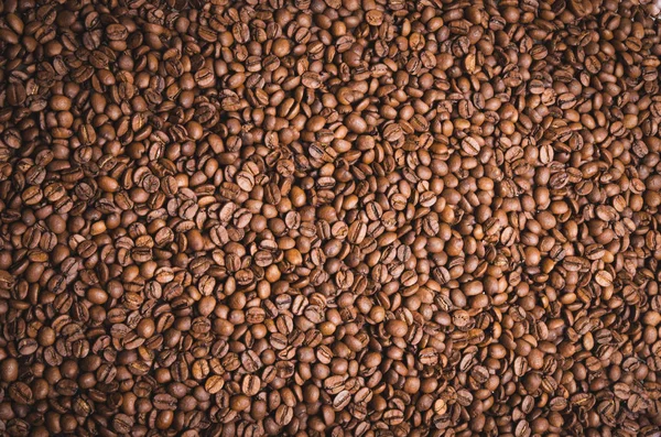 High resolution top view close up macro photo of look delicious dark roasted coffee beans, Flash light reflecting on the surface of the coffee beans make it look shinny beautiful and be nice for eat.