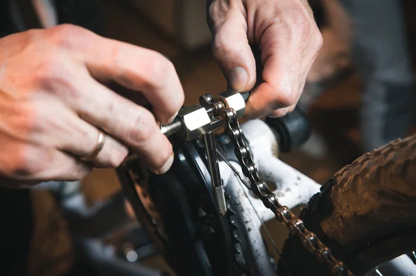 Bike service: mechanic serviceman repairman installing assembling or adjusting bicycle gear on wheel in workshop