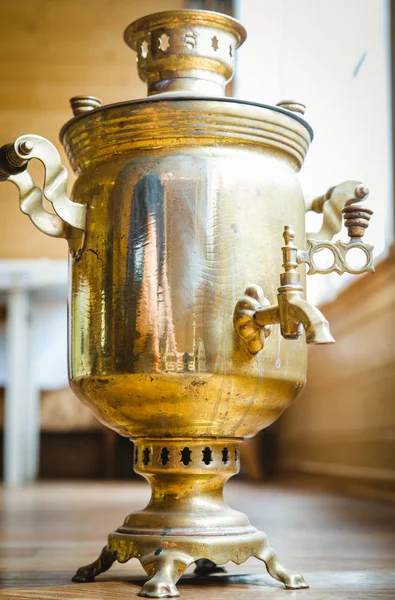 Velký starý samovar bronzu stojí na zemi a připravuje čaj. Proces výroby čaje samovar. Velká konvice se připravuje čaj ve venkovním prostoru. — Stock fotografie