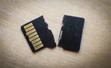 Broken destroyed micro sd card on white surface clipart