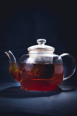 İşlem bira çay, çay töreni, taze demlendi siyah çay, sıcak yumuşak ışık, koyu arka plan.