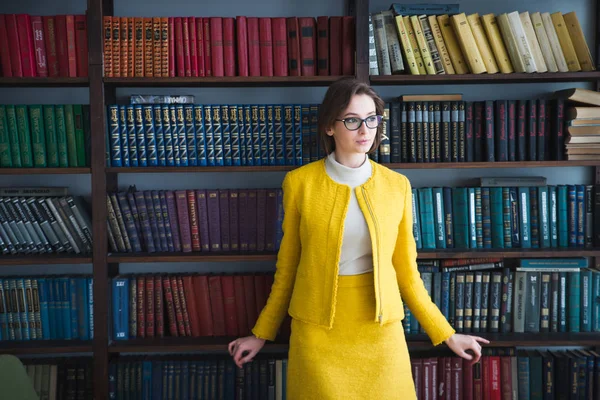 Halve lengte portret van mooie lachende vrouw in casual slijtage staande in boekhandel genieten van literatuur, aantrekkelijke Aziatische vrouw poseren in de buurt van planken met boeken in College bibliotheek kijken naar camera — Stockfoto