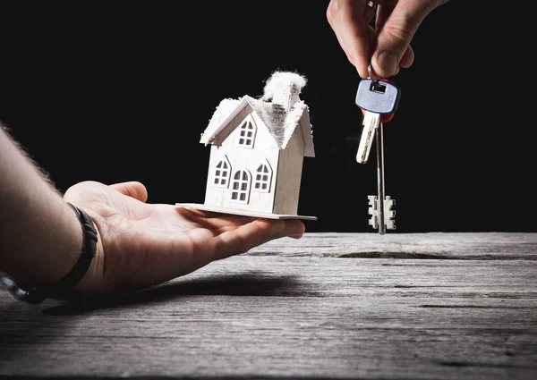 Toy house with key on wooden background