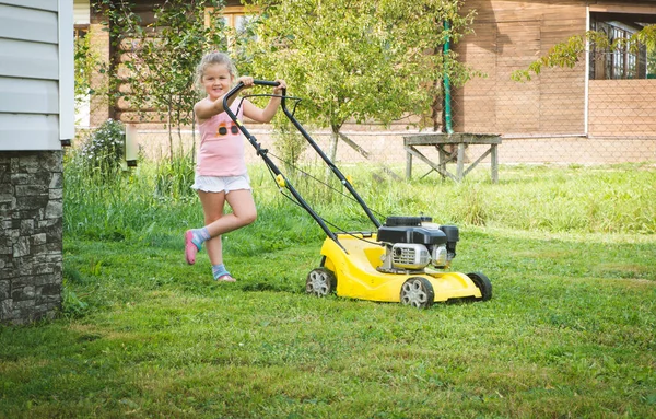 Kleines Blondes Kleinkind Spielt Sonnigem Tag Mit Rasenmähermaschine Sommergarten lizenzfreie Stockfotos