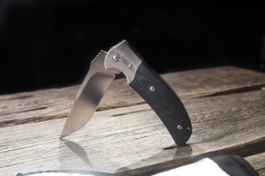 Bir kenarı ahşap arka planda katlanmış çakı.