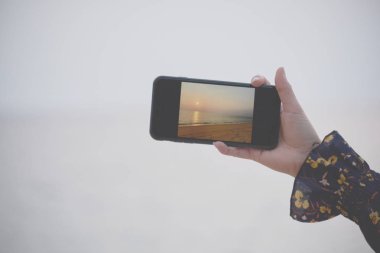 bulanıklık arka plan ile cep telefonu ile günbatımı bir atış almak