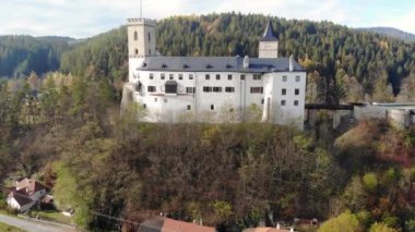 Sonbahar ormanlarıyla çevrili bir tepedeki beyaz şato. Rozmberk nad Vltavou, Güney Bohemya, Çek Cumhuriyeti 4K