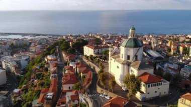 Deniz kıyısındaki güzel İtalyan şehrinde İHA uçuşu. Evlerin ve kiliselerin manzarası. Madonna della Costa. San Remo, İtalya. 4K içinde hava görüntüsü