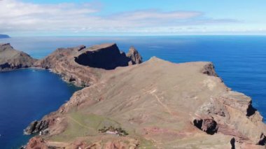 Güneşli bir yaz gününde okyanustaki bir adanın insansız hava aracı görüntüsü. Mavi gökyüzü ve turkuaz okyanus. Madeira, Portekiz 4K 'da.