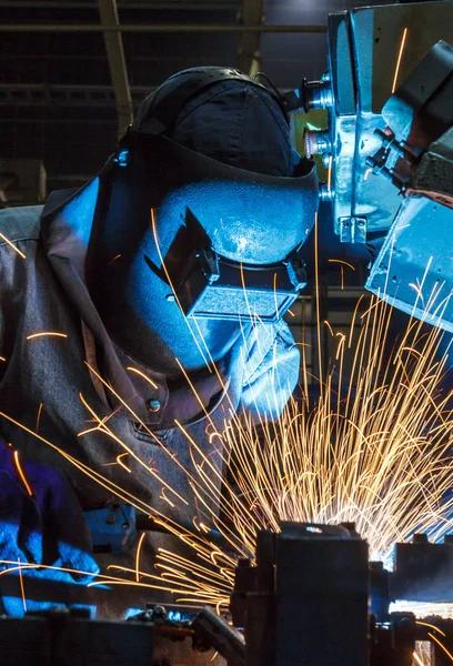 worker with protective mask welding metal