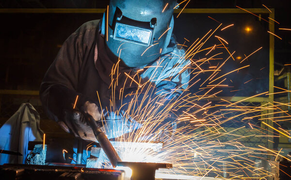 работник с защитной маской сварки металла