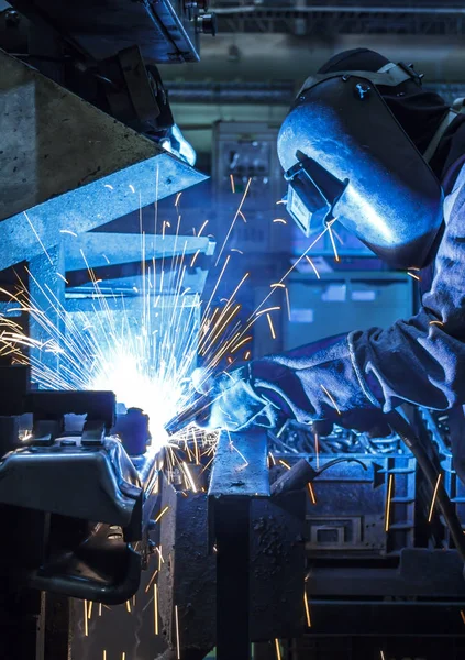 Industrial steel worker speeds motion in factory worker with protective mask welding metal