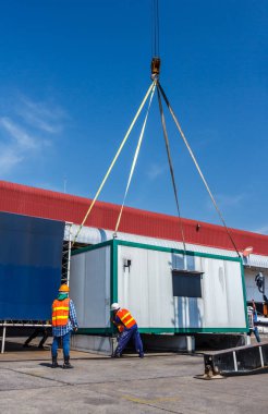 İşçiler küçük ofis dolapları vinç ile hareket ediyor.