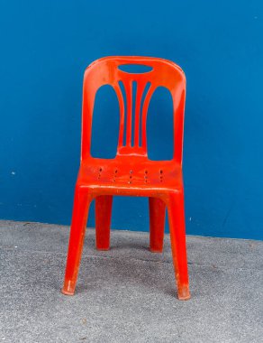 Yerde bir kırmızı plastik sandalye.