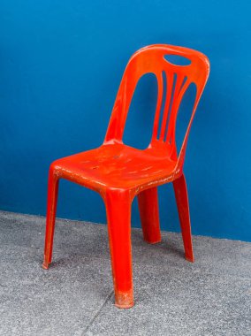 Yerde bir kırmızı plastik sandalye.